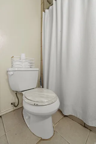 Full bath with a shower with curtain and tile patterned flooring