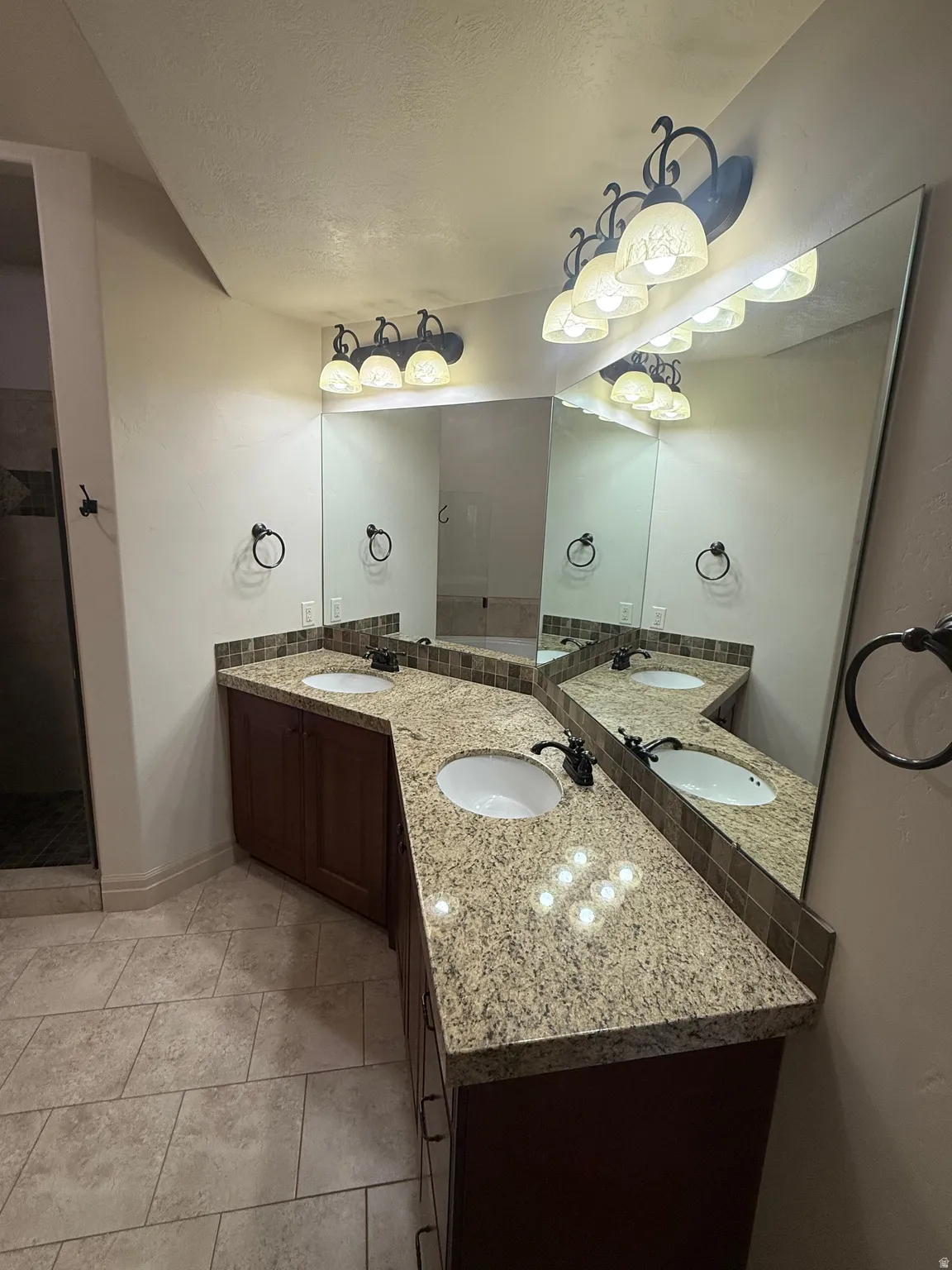 Full bath with double vanity and a textured ceiling