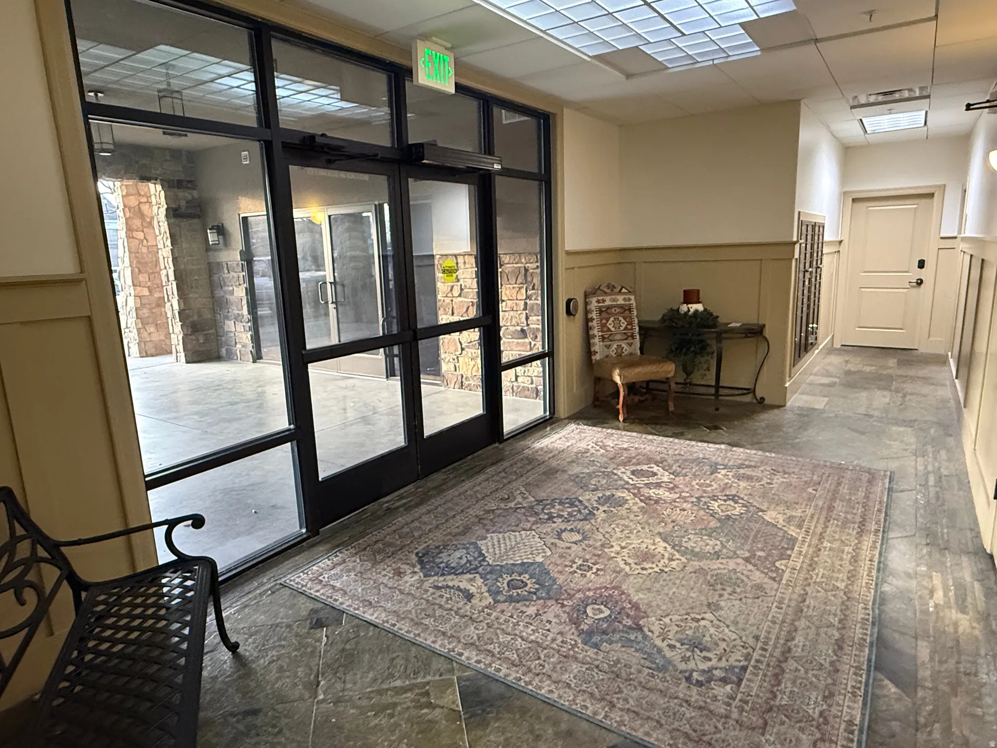 Community lobby featuring wainscoting, a paneled ceiling, and floor to ceiling windows
