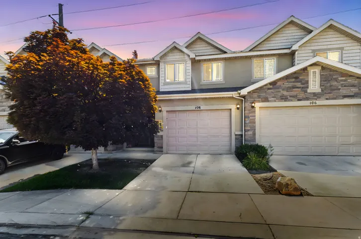 View of front of house featuring driveway, stone siding, and an attached garage