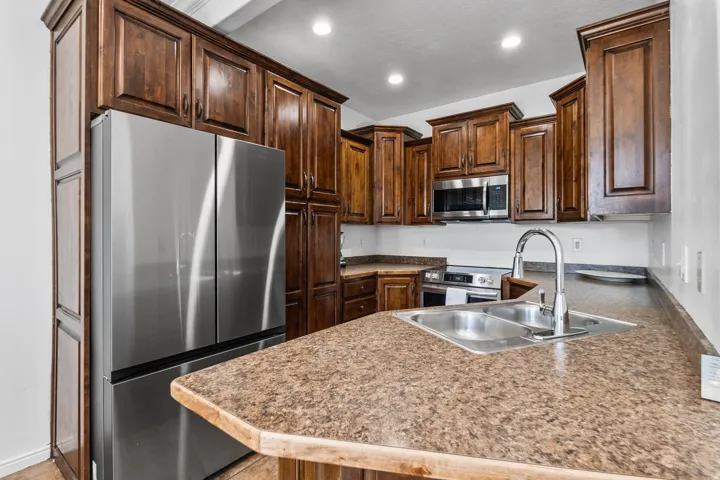 Kitchen with stainless steel appliances, dark wood finish cabinets, and recessed lighting