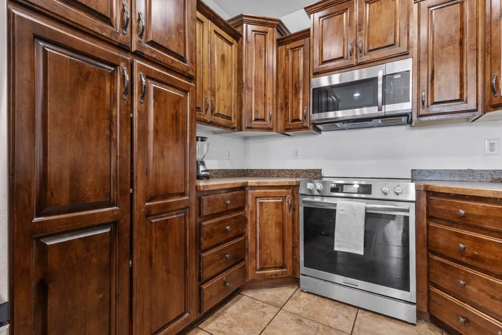Kitchen with stainless steel appliances, light tile patterned floors, and dark countertops