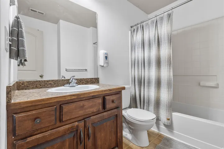 Bathroom with shower / bath combo with shower curtain, vanity, and light tile patterned flooring