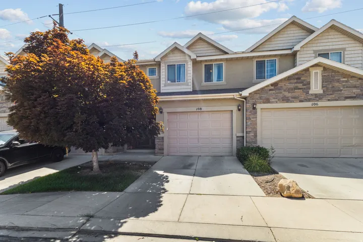 View of front of property featuring driveway, stone siding, and a garage