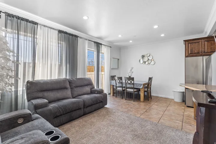 Living room with ornamental molding, recessed lighting, light tile patterned floors, and light colored carpet