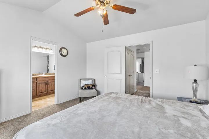 Bedroom with carpet, lofted ceiling, ensuite bath, and ceiling fan