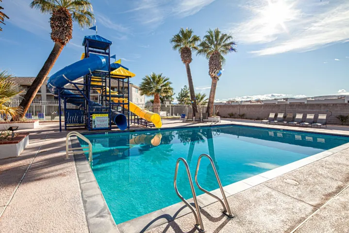 Community pool with a water slide and a patio