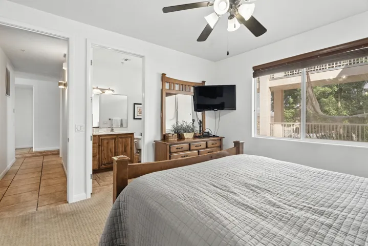 Bedroom featuring a ceiling fan, light carpet, and ensuite bathroom