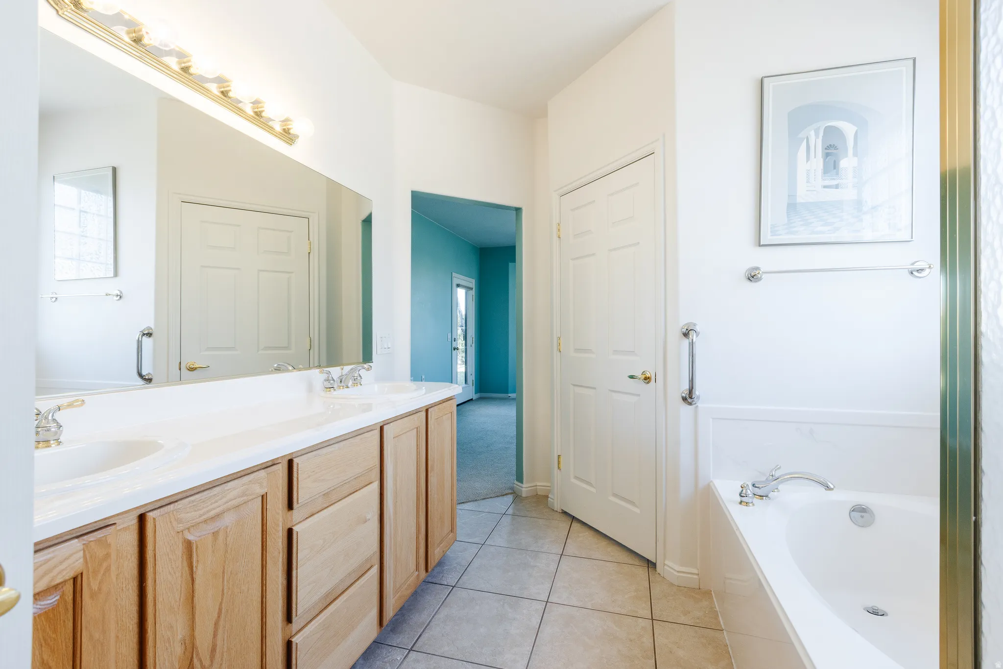 Bathroom with double vanity, a garden tub, and light tile patterned flooring