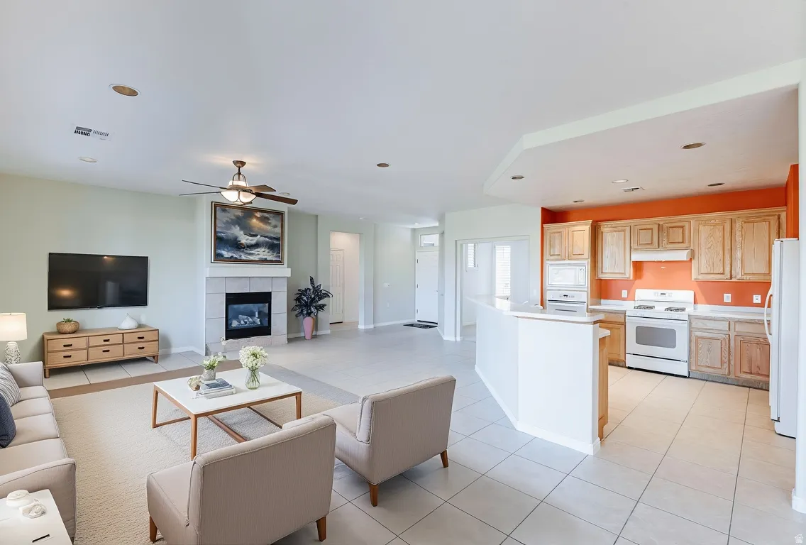 Living area with ceiling fan, a tiled fireplace, recessed lighting, and light tile patterned floors