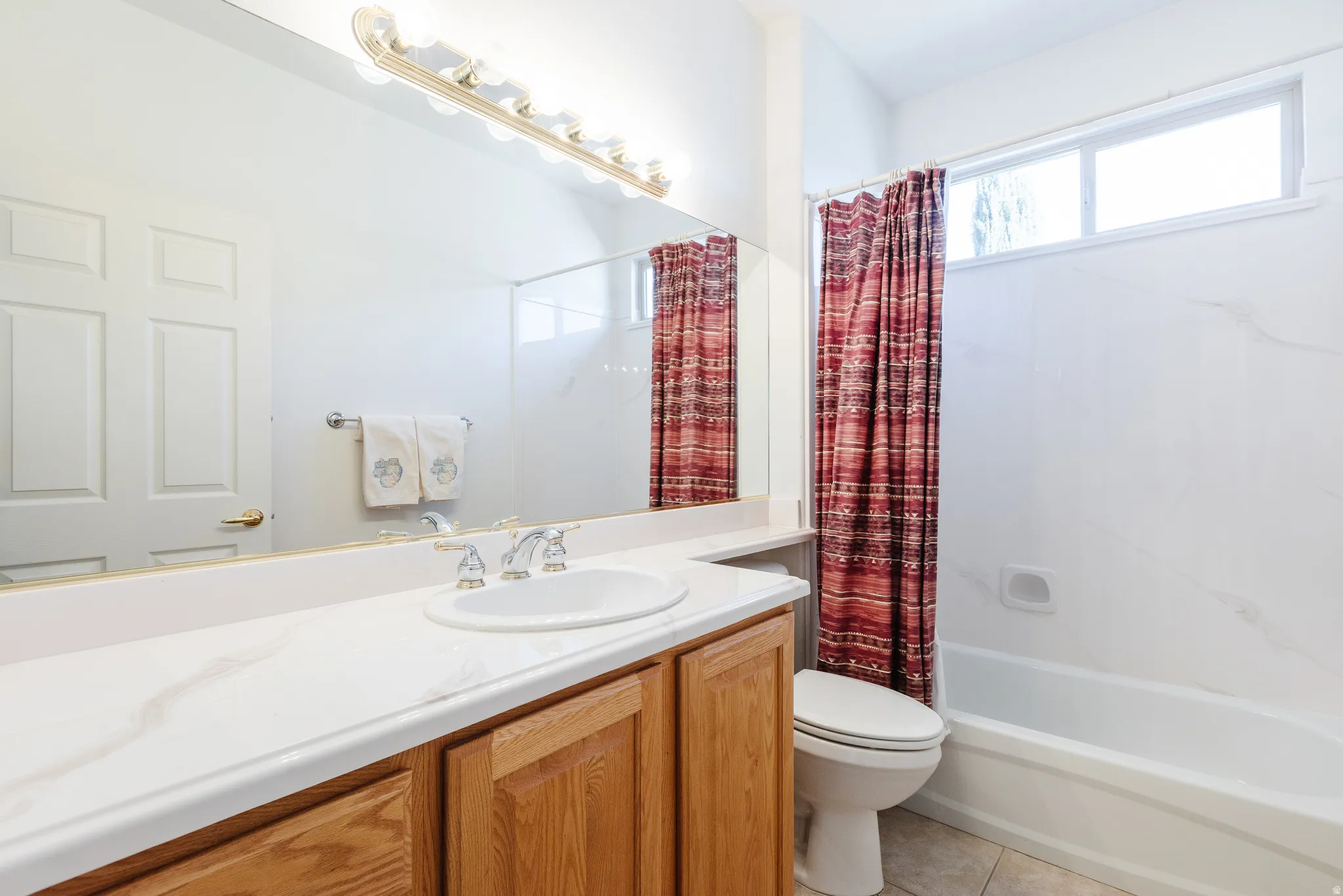 Bathroom featuring shower / tub combo, vanity, and light tile patterned flooring