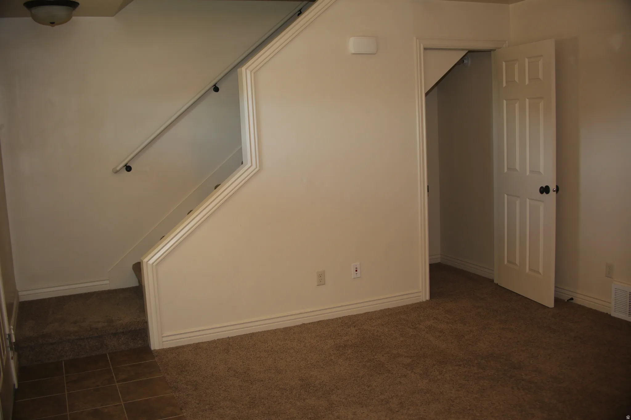 Unfurnished room featuring dark colored carpet and dark tile patterned flooring