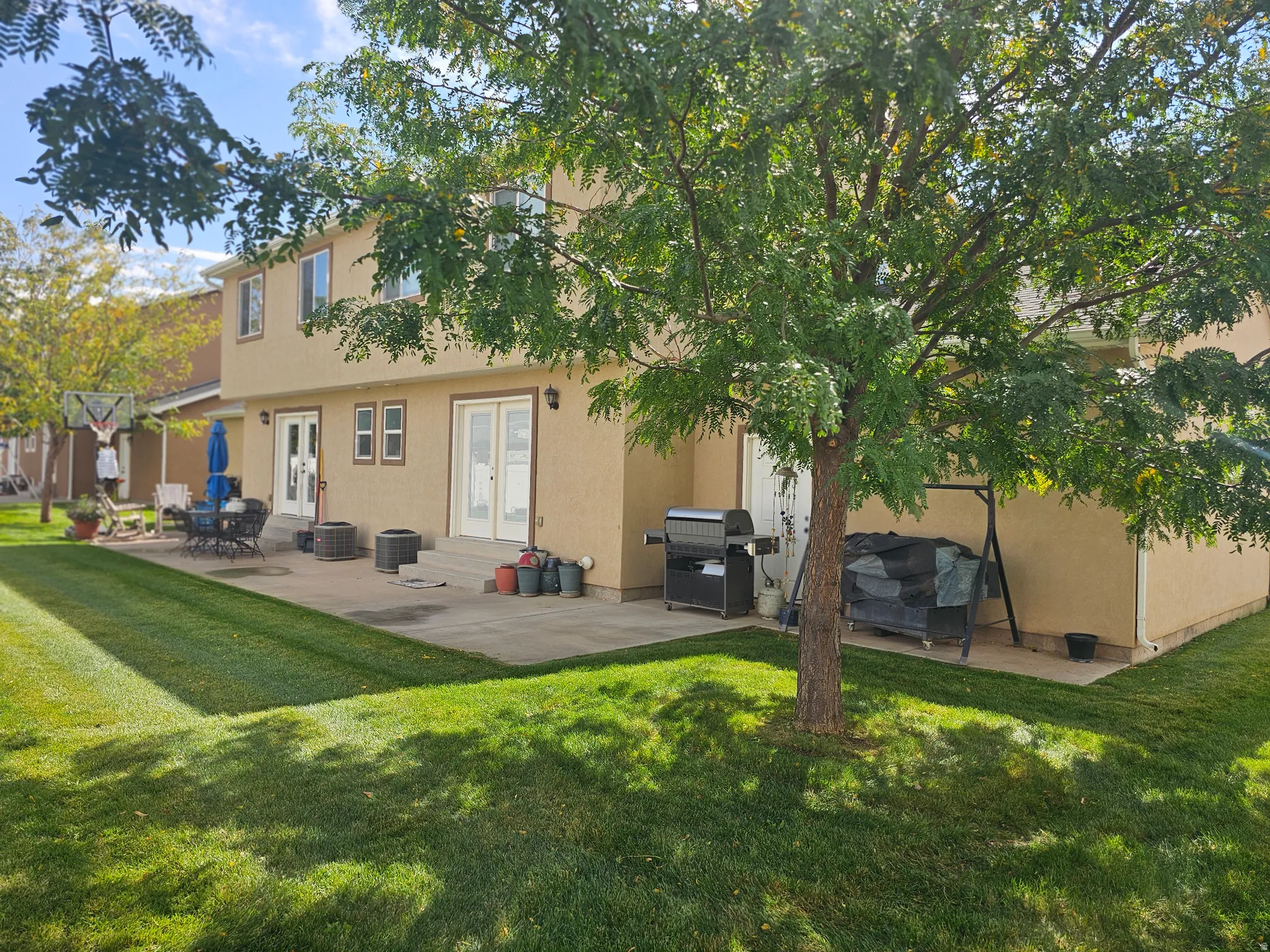 Rear view of property with a patio, a yard, and stucco siding