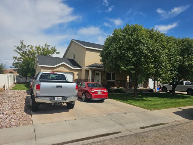 View of front facade with concrete driveway, stucco siding, and stone siding