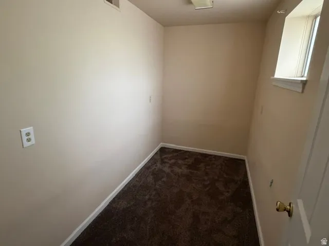 Compact interior space with light-toned walls, brown carpet flooring, and white baseboards