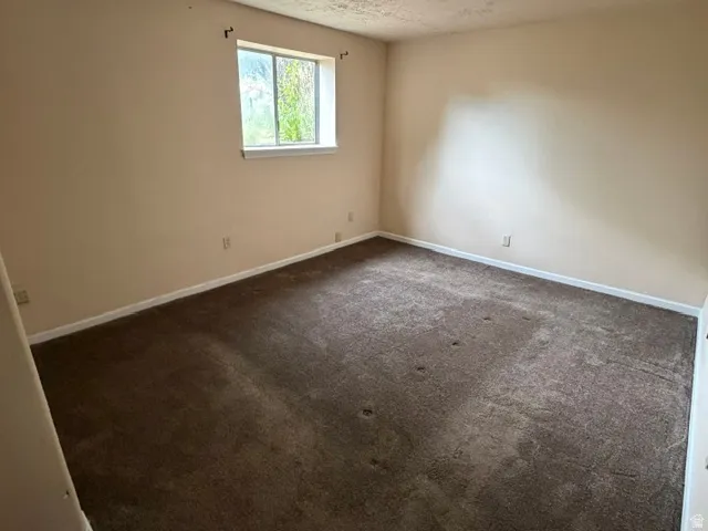 Room featuring a window with white trim, light beige walls, and brown carpeting