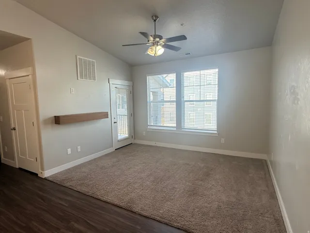 Unfurnished room with ceiling fan, vaulted ceiling, and dark wood finished floors