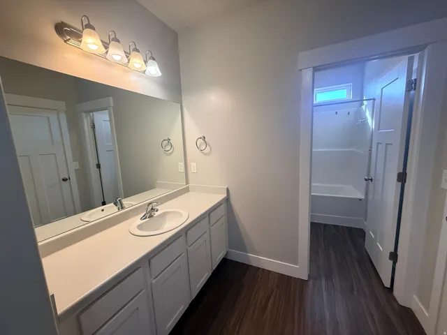 Bathroom featuring vanity, shower / bathtub combination, and dark wood finished floors
