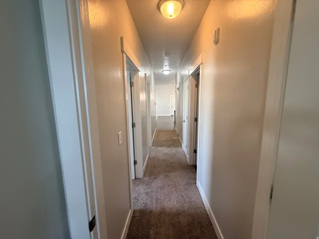 Corridor with carpet flooring and baseboards