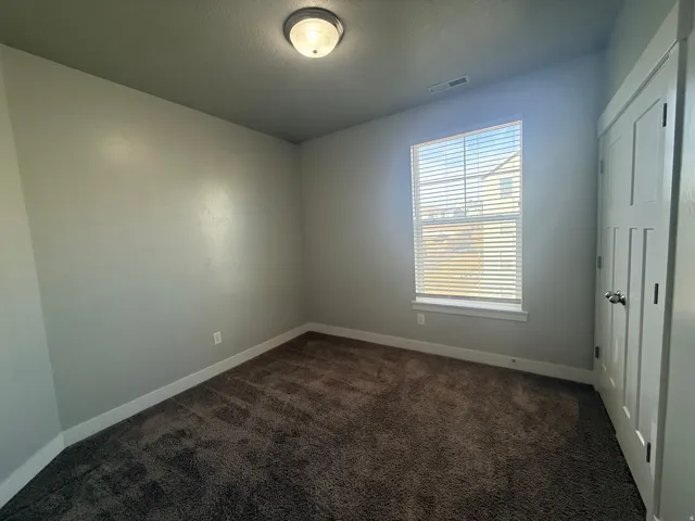 Unfurnished room with dark carpet and baseboards