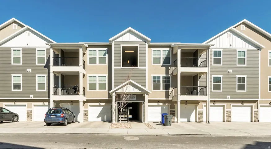 View of apartment building / complex featuring a garage and driveway