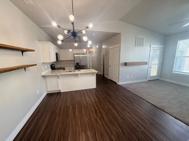 Kitchen with light countertops, white cabinetry, open floor plan, vaulted ceiling, and a peninsula