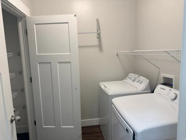 Laundry area with washer and clothes dryer and dark wood finished floors