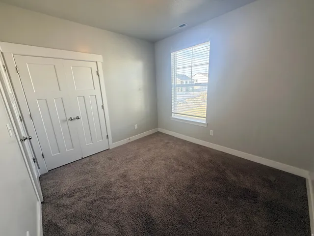 Unfurnished bedroom featuring a closet and dark colored carpet