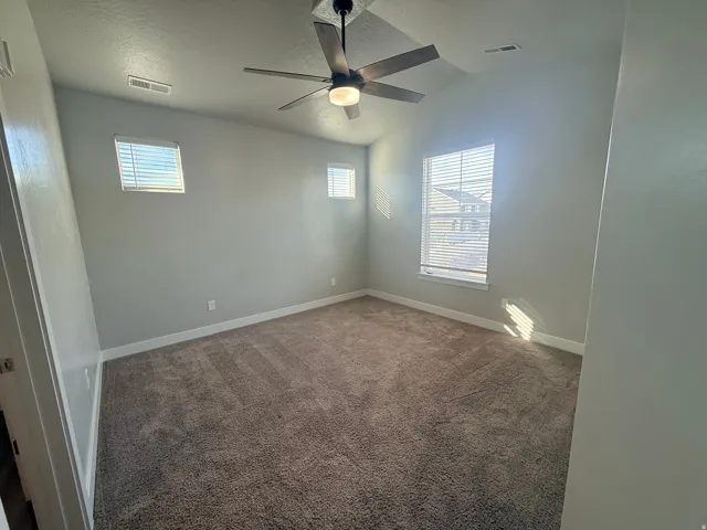 Spare room featuring dark carpet and a ceiling fan