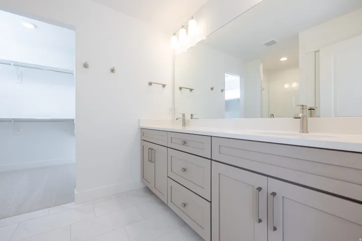 Dual vanity featuring light gray shaker cabinetry, brushed nickel hardware, and a white countertop