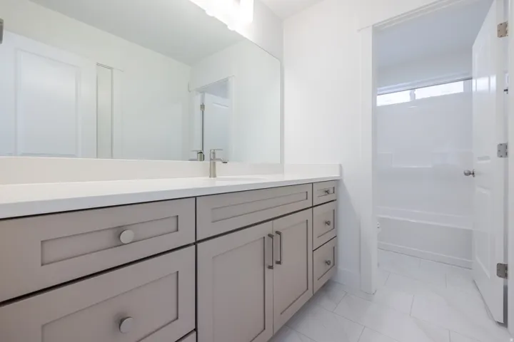 Spacious vanity with light gray cabinetry, white countertop, and brushed nickel hardware