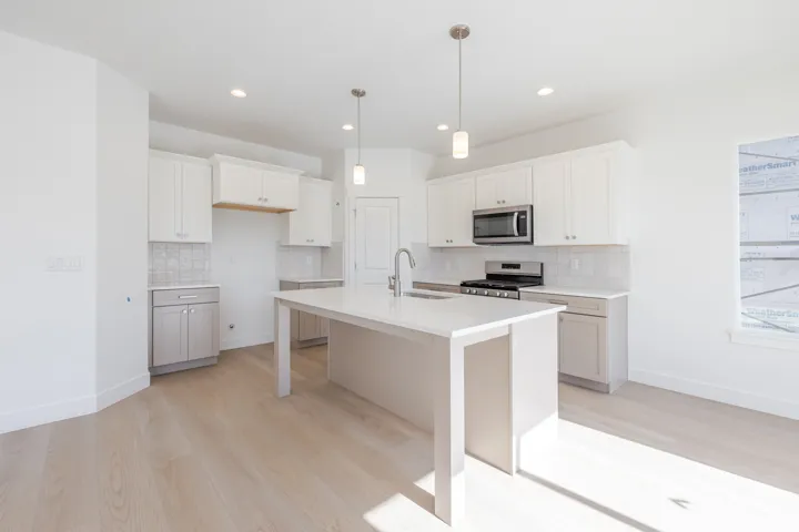 Contemporary kitchen featuring a spacious island, white cabinetry, stainless steel appliances, and wood-finish flooring