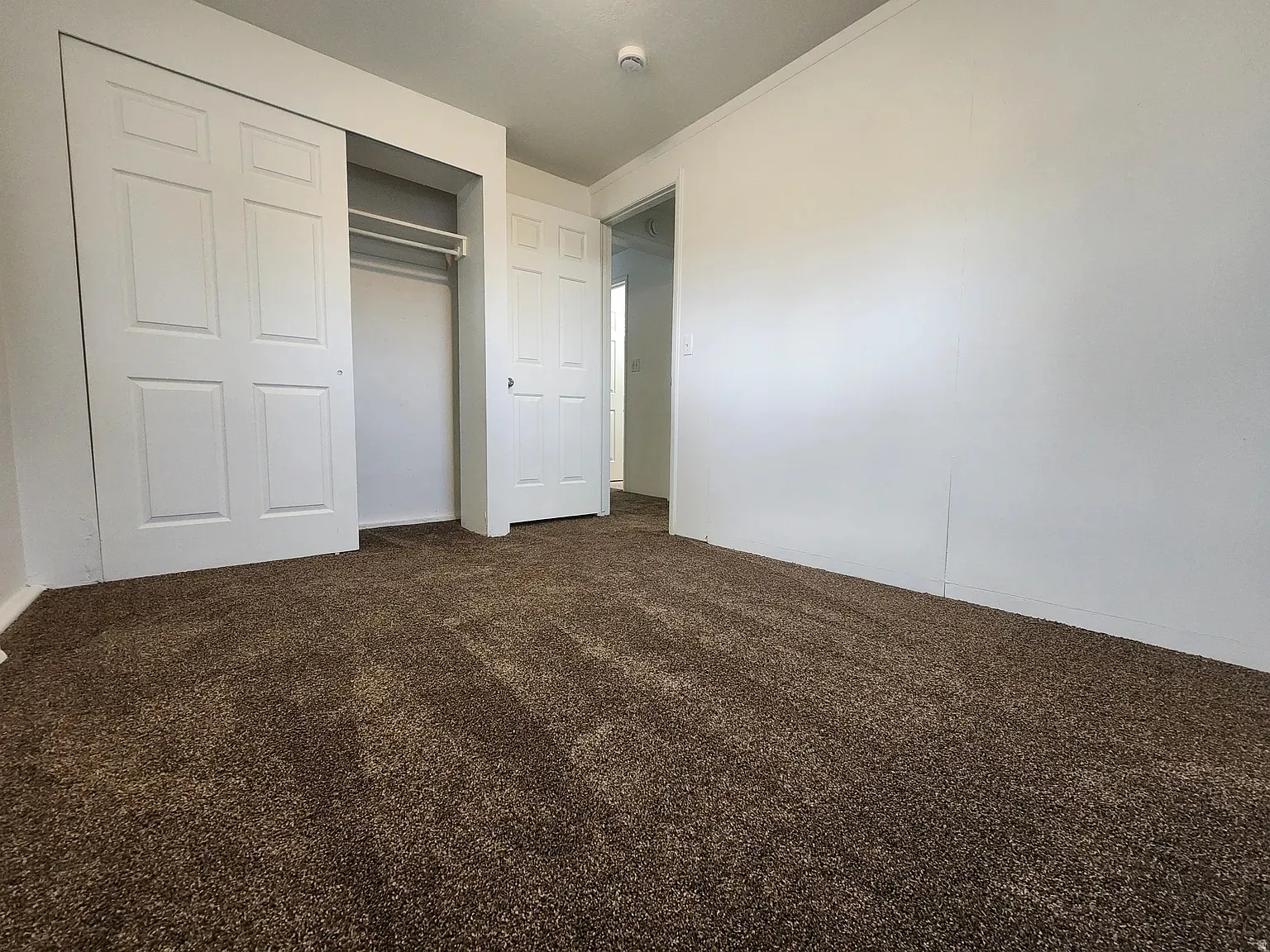 Unfurnished bedroom featuring dark carpet, a closet, and crown molding