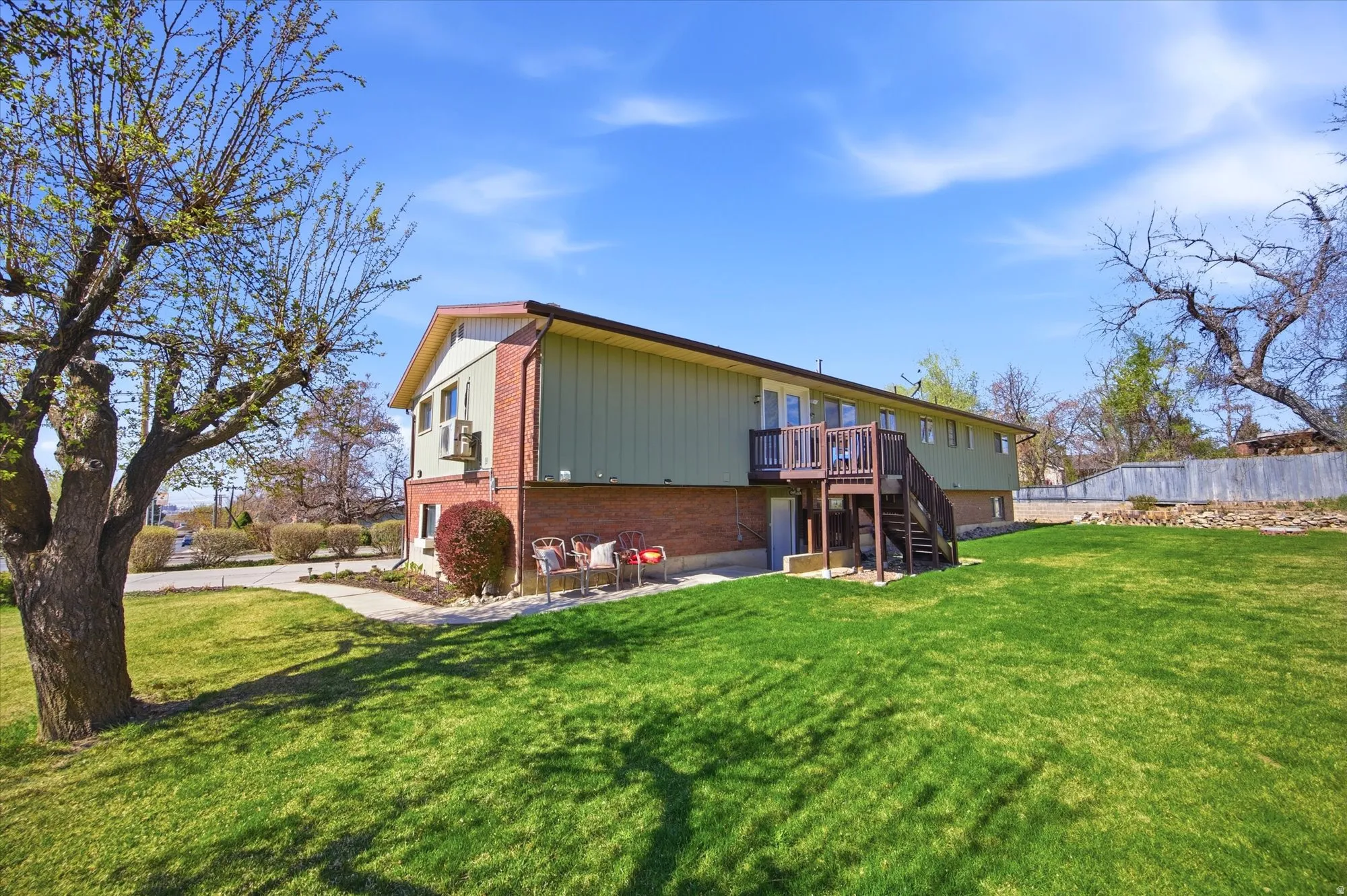 Rear view of property with brick siding, a patio area, and a wooden deck