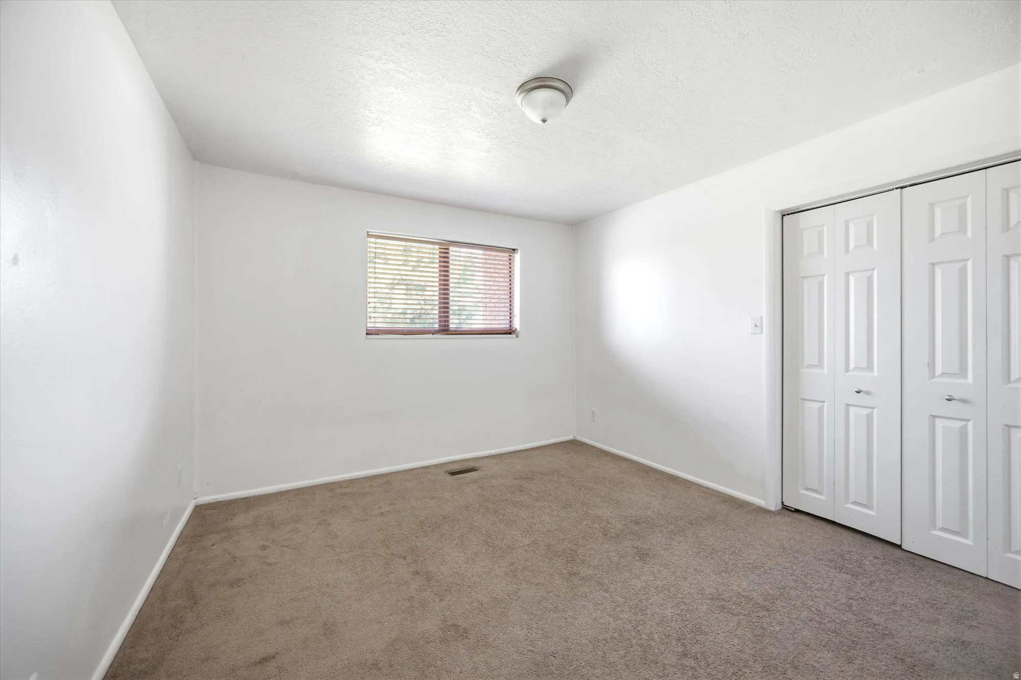 Unfurnished bedroom with a closet, carpet, and a textured ceiling