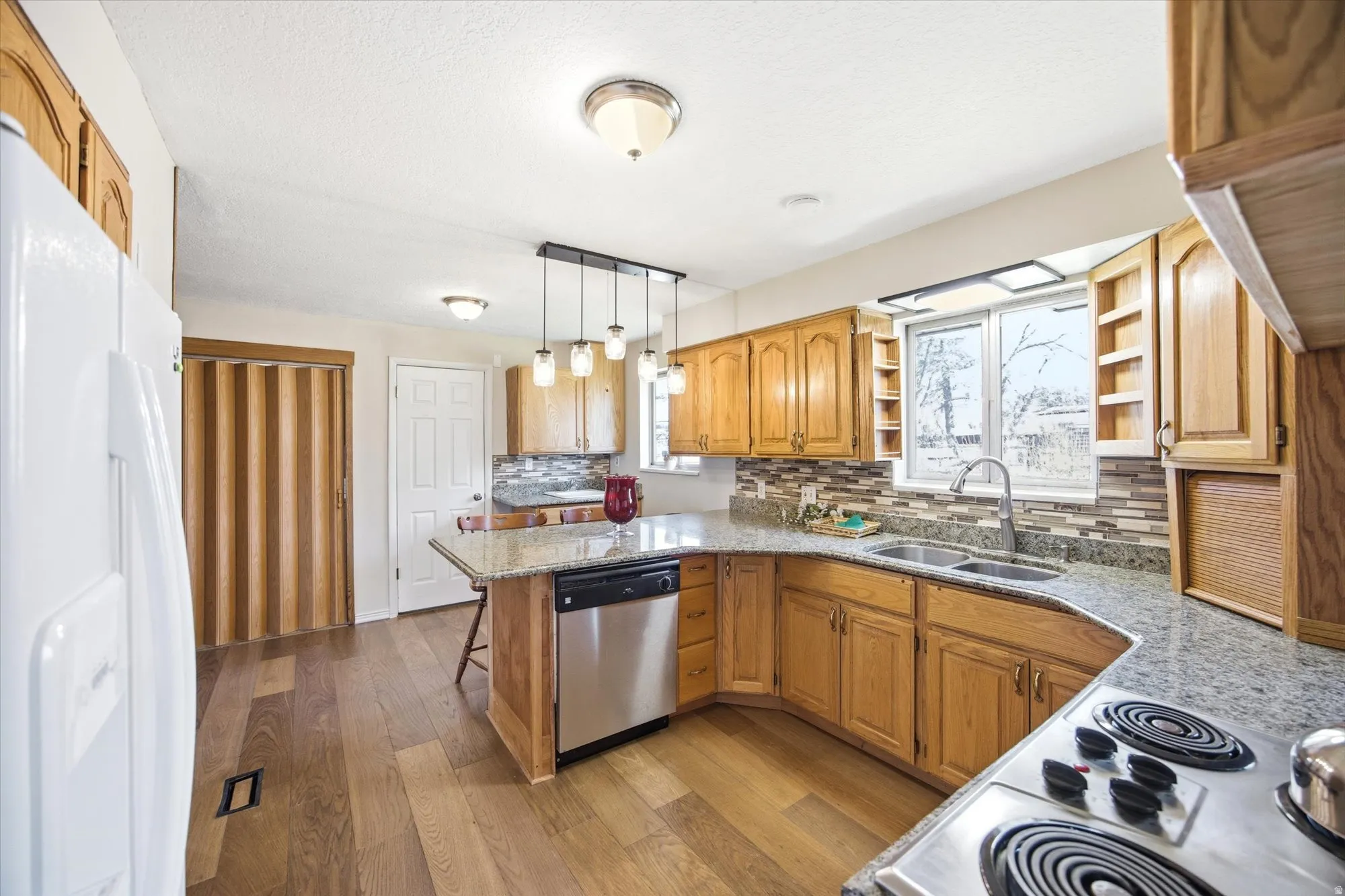 Kitchen featuring a peninsula, stainless steel appliances, decorative backsplash, a breakfast bar, and wood finish cabinetry