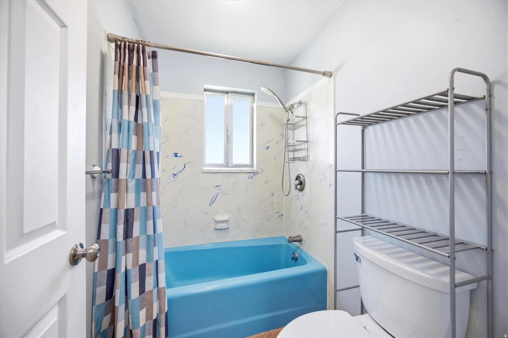 Bathroom featuring toilet and shower / bath combo with shower curtain