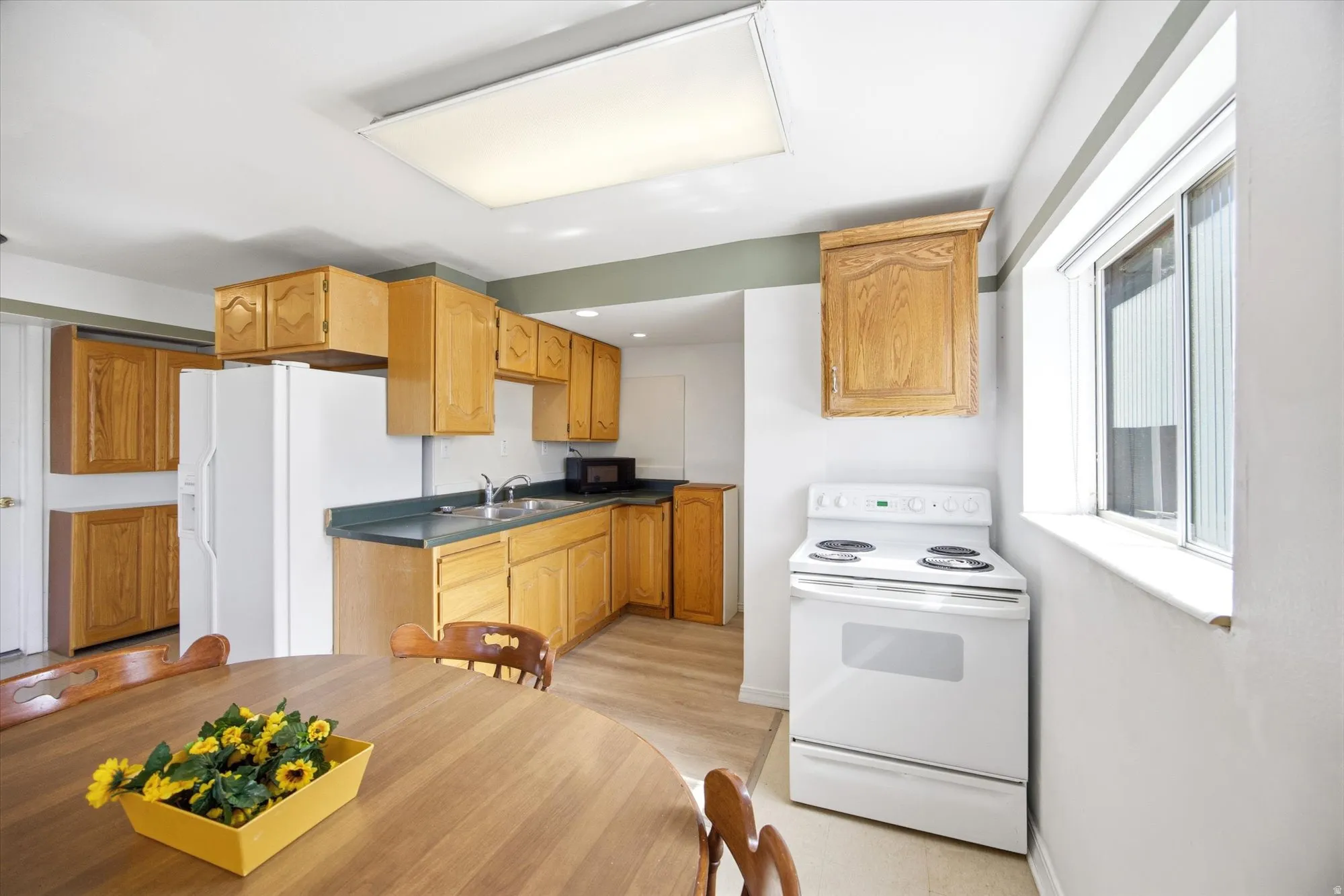 Kitchen featuring white appliances, dark countertops, wood finish cabinets, and recessed lighting