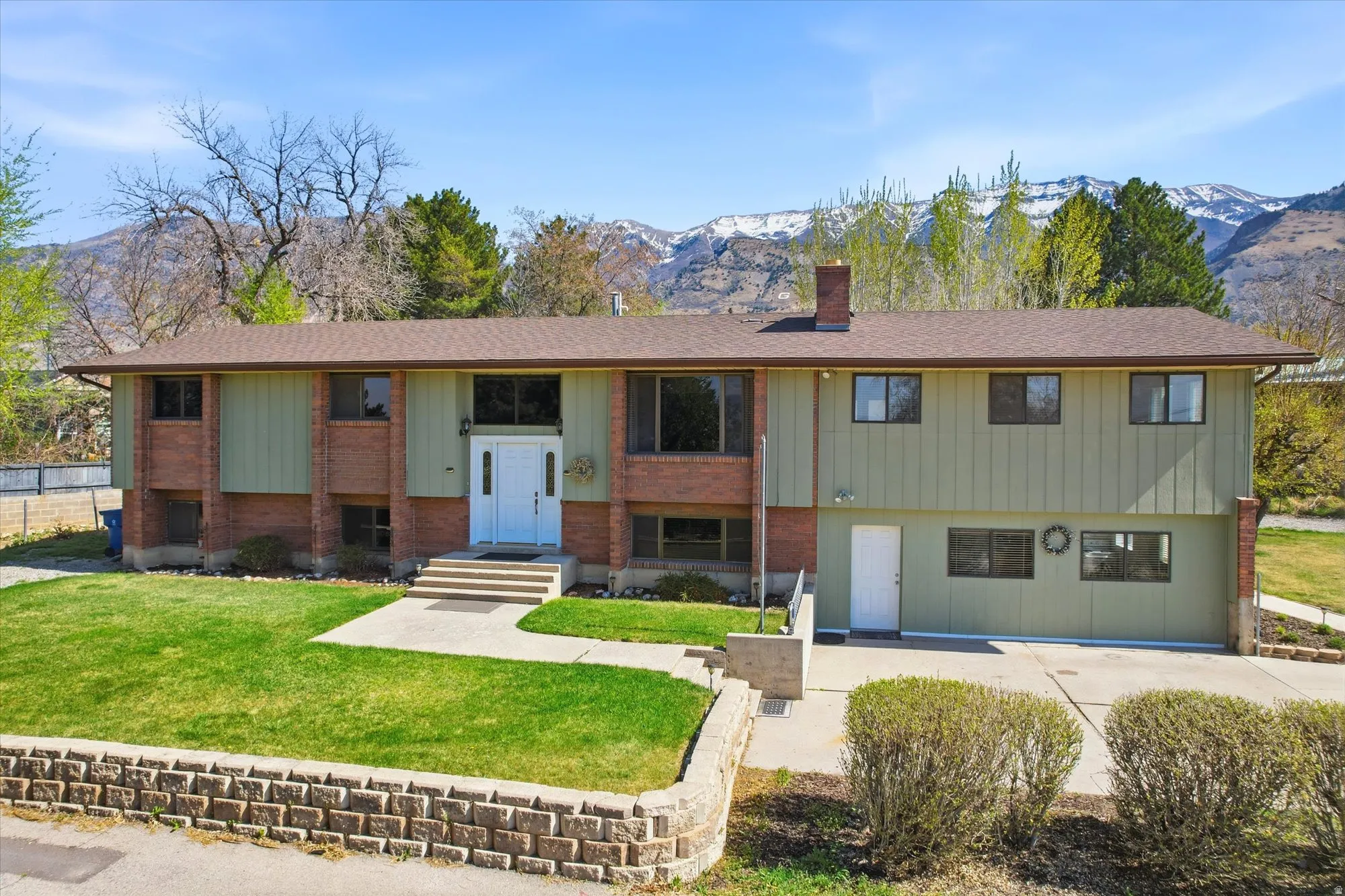 Split foyer home featuring a mountain view, a front yard, a chimney, and board and batten siding