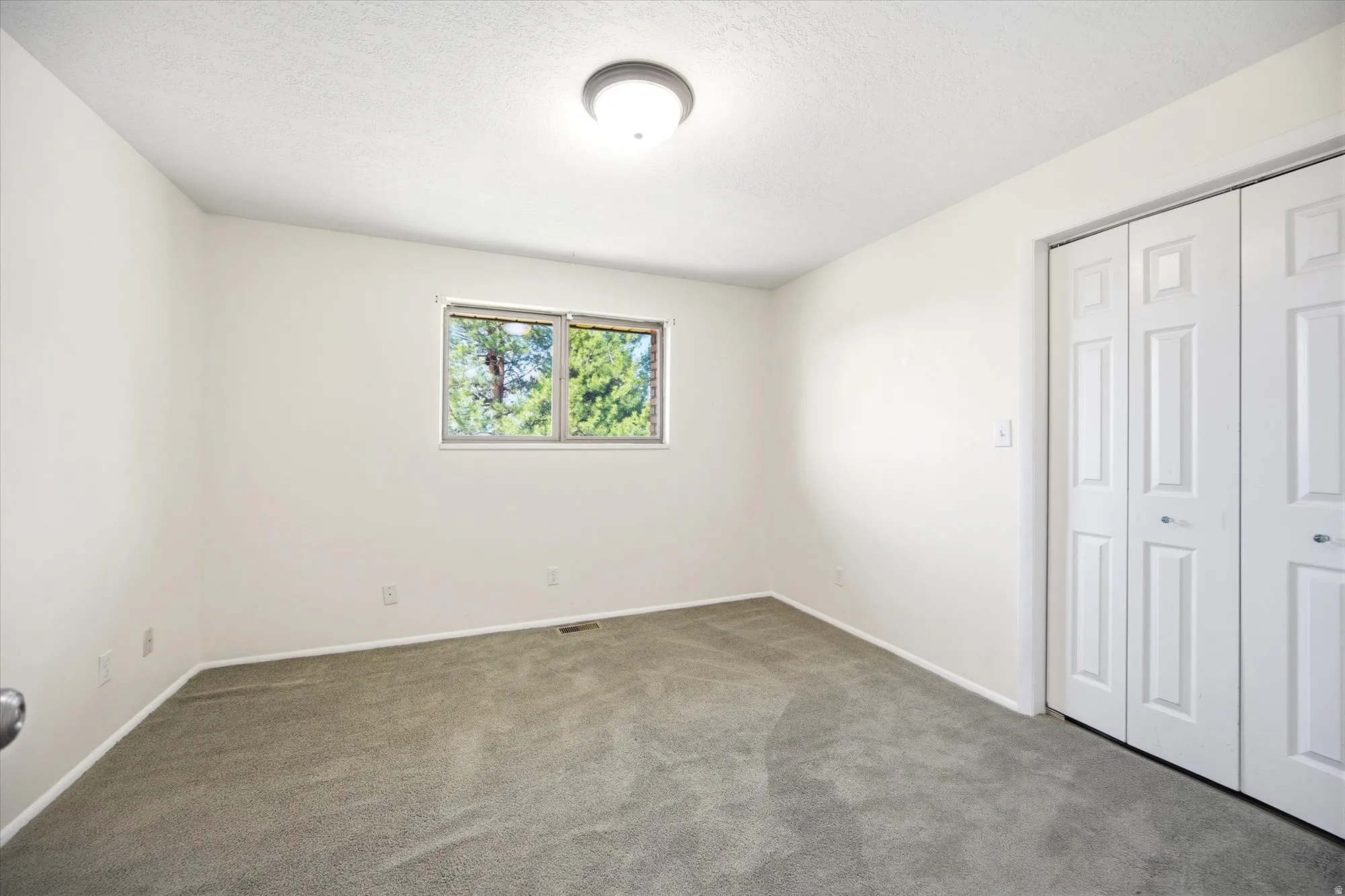 Unfurnished bedroom with carpet flooring, a closet, and a textured ceiling
