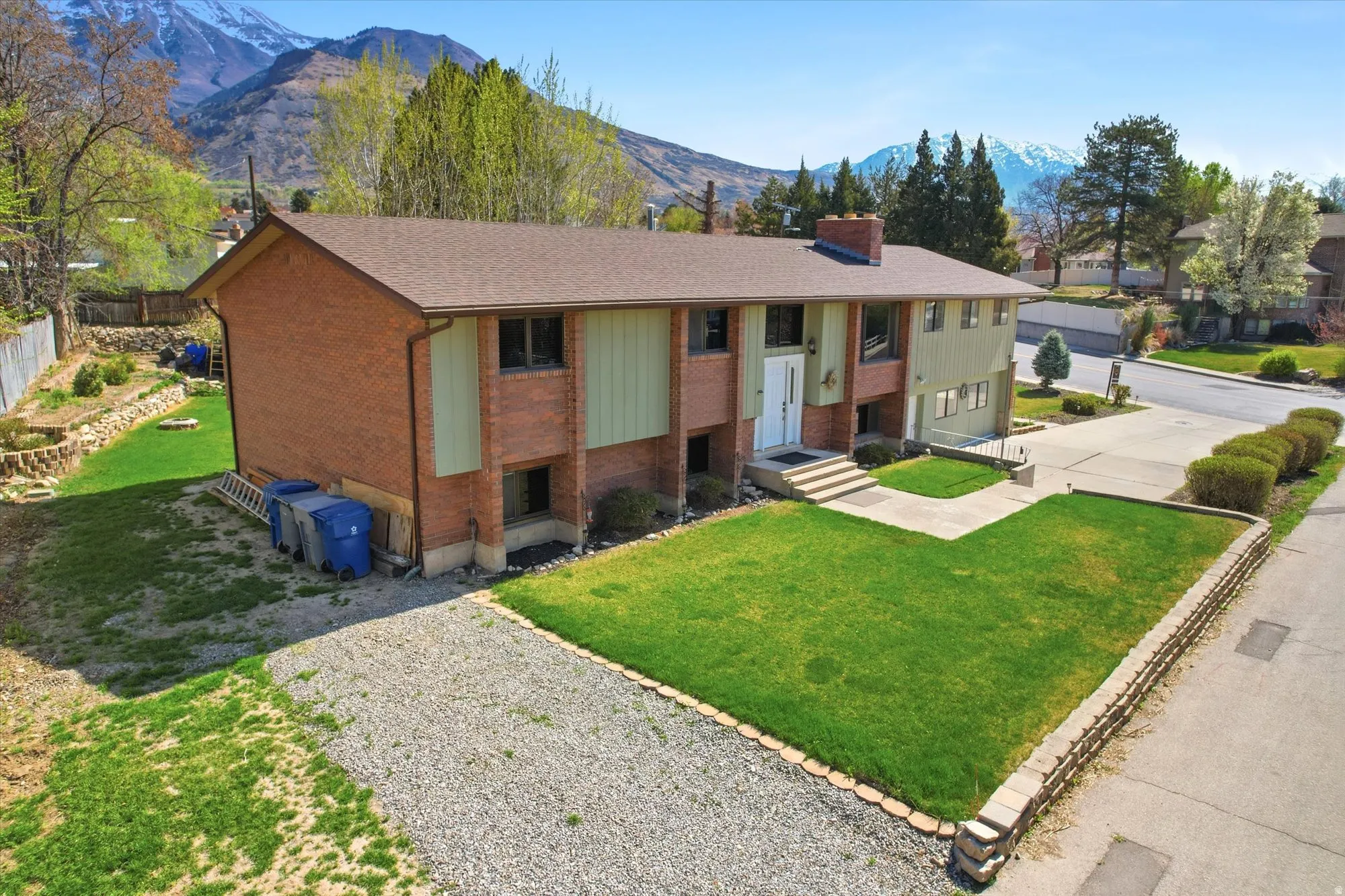 View of front of home with brick siding, a front lawn, a mountain view, and a chimney