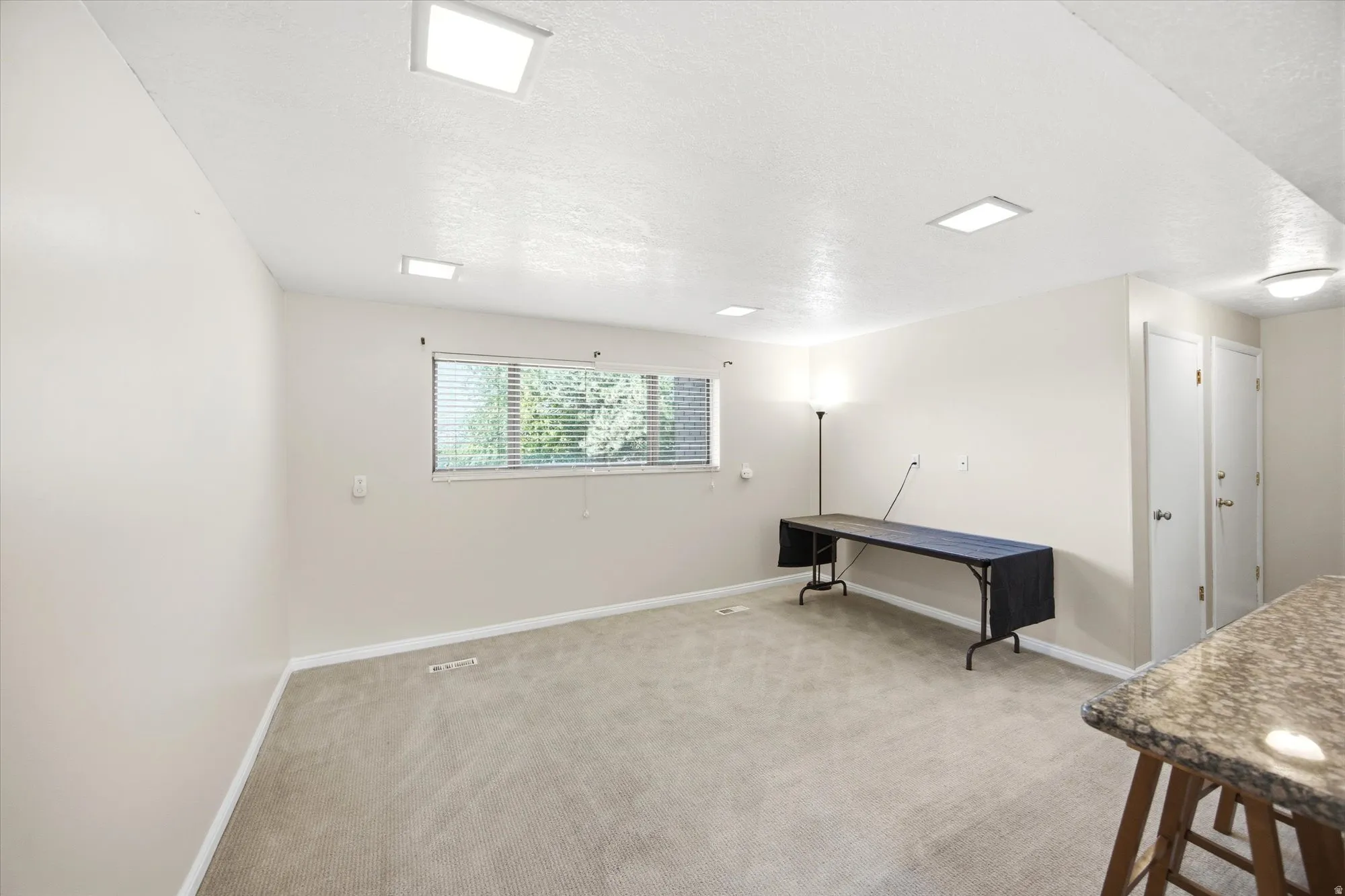 Basement with a textured ceiling and light colored carpet