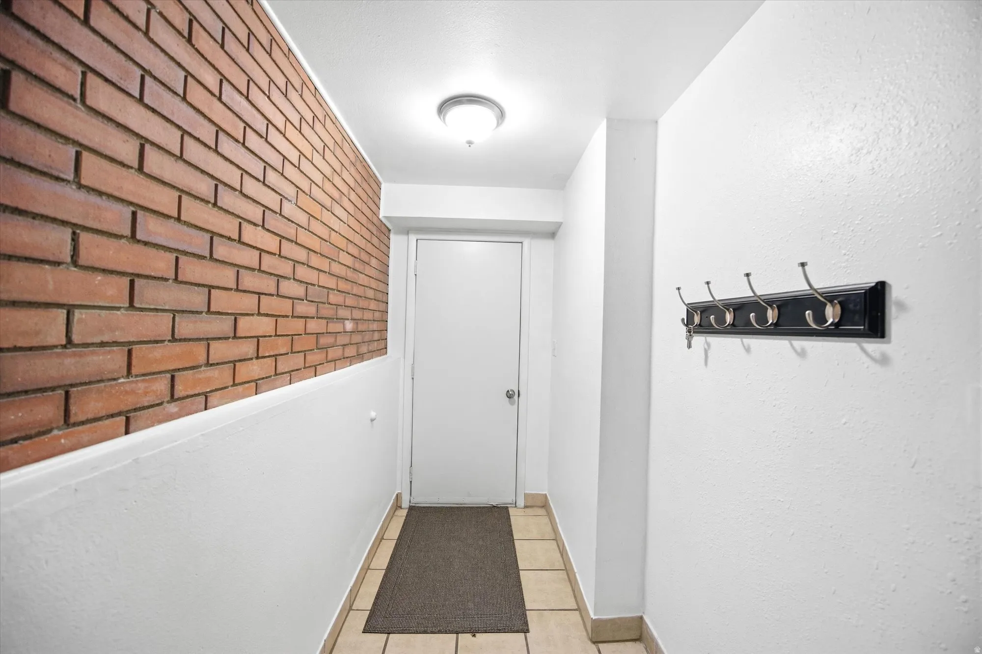 Hall with brick wall and light tile patterned flooring