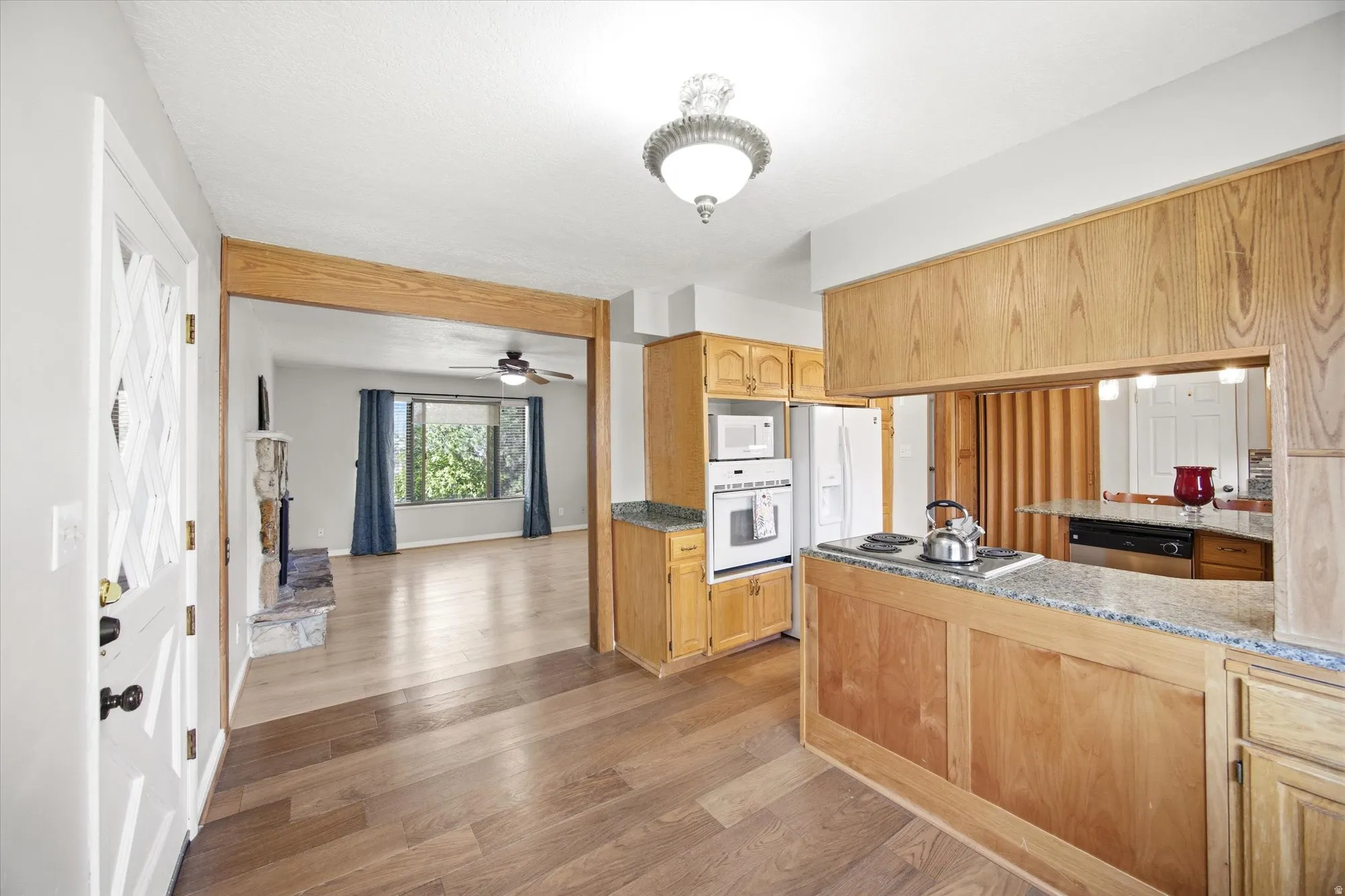 Kitchen featuring light wood-style flooring, stainless steel appliances, light wood finish cabinetry, and light stone counters