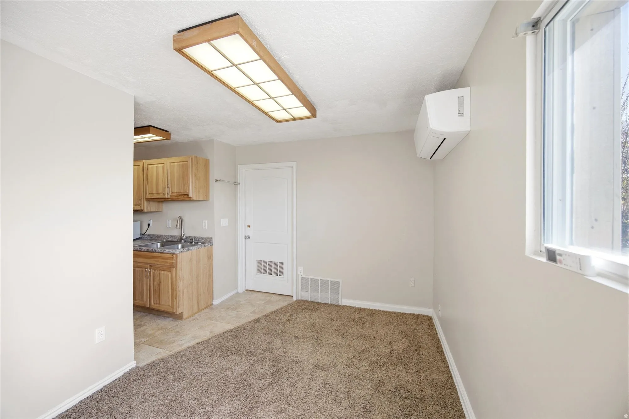 Kitchen with light carpet, light wood finish cabinets, and a textured ceiling
