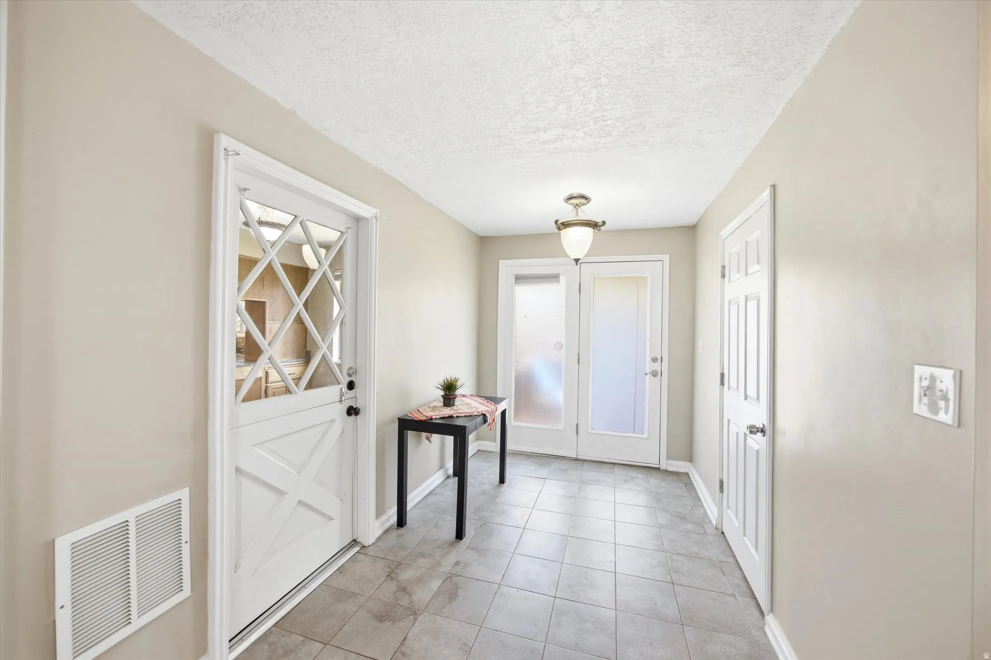 Doorway featuring a textured ceiling and tile patterned flooring