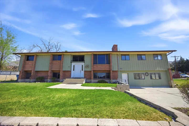 Bi-level home featuring a front yard, brick siding, a chimney, and entry steps