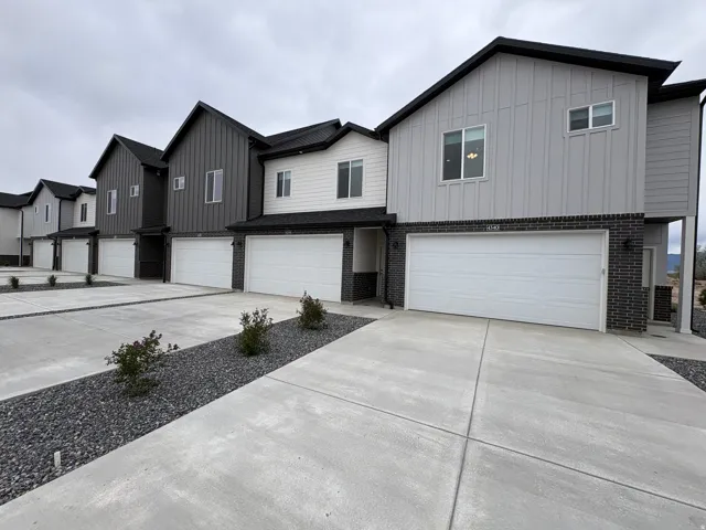 View of front of house with board and batten siding, a garage, brick siding, and concrete driveway
