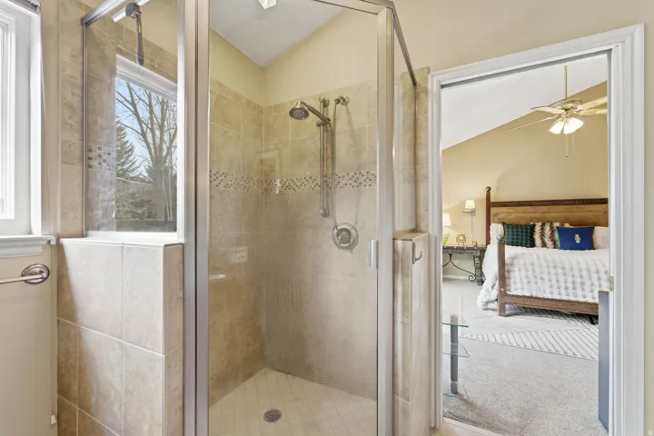 Bathroom featuring ensuite bathroom, vaulted ceiling, a stall shower, light carpet, and a ceiling fan