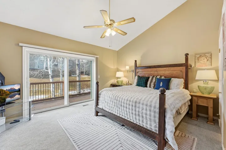 Bedroom with access to exterior, light carpet, lofted ceiling, and a ceiling fan